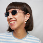 Klammeraffe No.11 bifocal reading sunglasses in pearl rosé color with longer temples, worn by a woman on a white background.