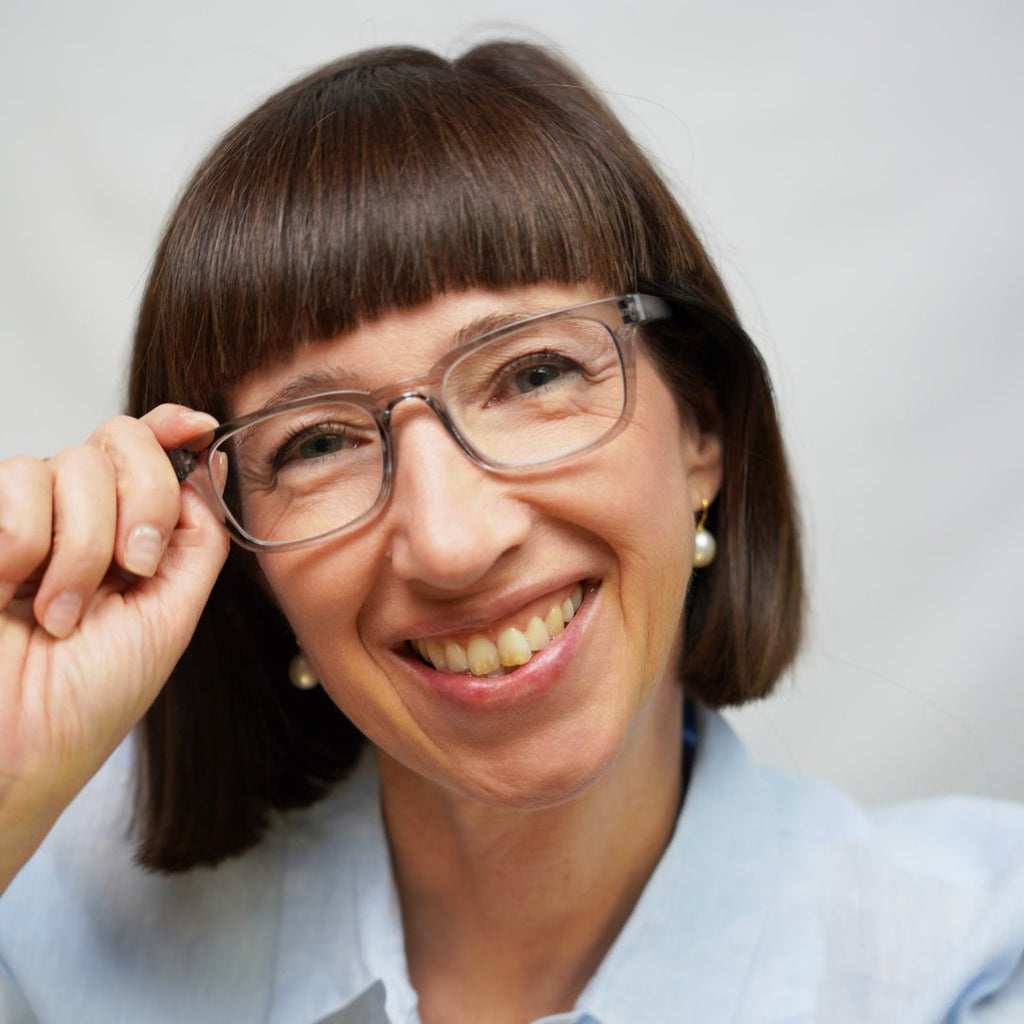 Klammeraffe No.11 blue light reading glasses in cloud color with longer temples, worn by a woman on a white background.