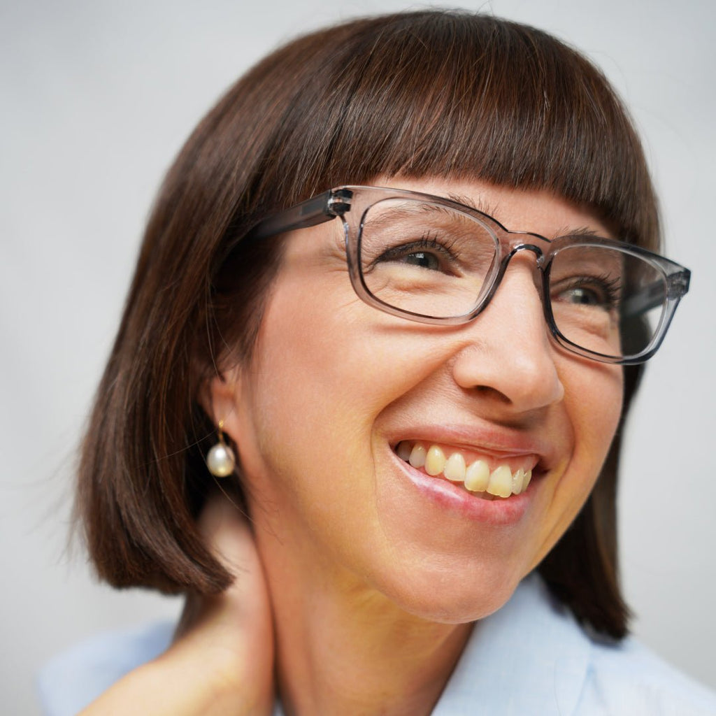 Klammeraffe No.11 reading glasses in cloud color with longer temples, worn by a woman on a white background.