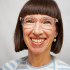 Klammeraffe No.01 reading glasses in pearl rosé color with longer temples, worn by a woman on a white background.