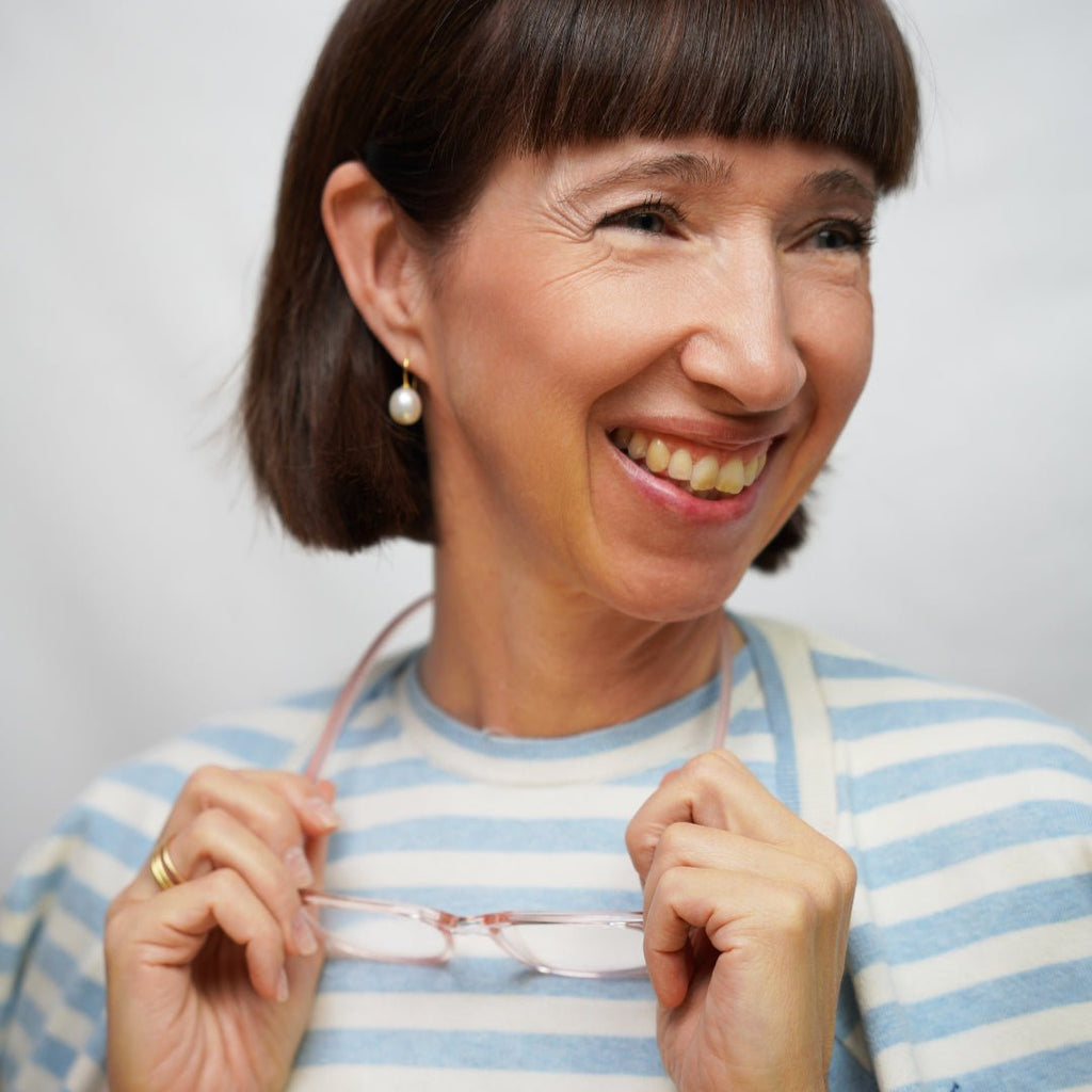 Klammeraffe No.01 reading glasses in pearl rosé color with longer temples, worn by a woman on a white background.