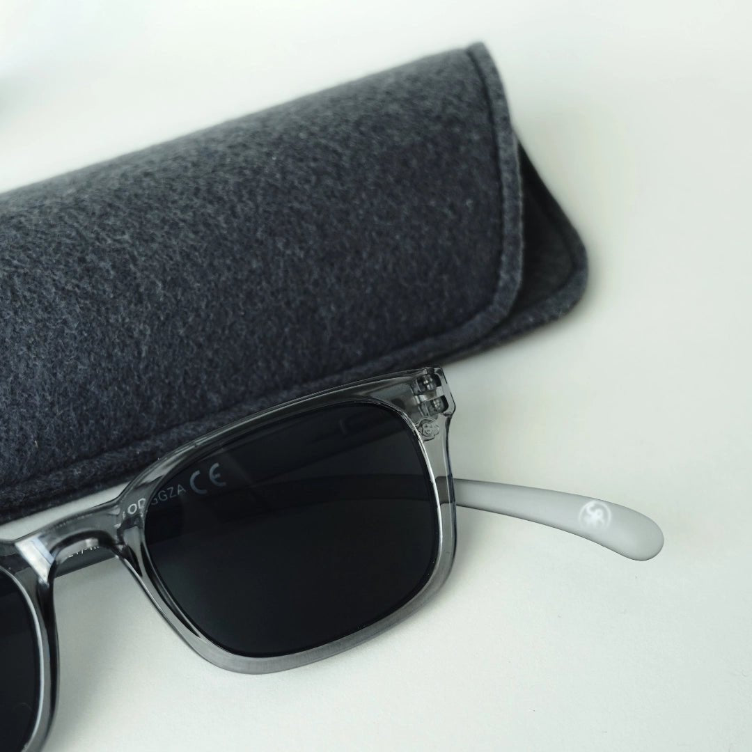 Klammeraffe No.11 sunglasses in cloud color with longer temples together with the case on a gray underground.
