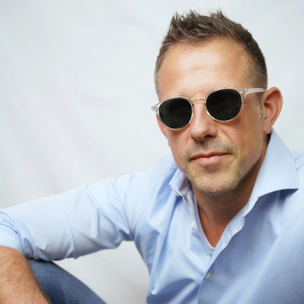 Klammeraffe No.12 bifocal reading sunglasses in crystal color with longer temples, worn by a man on a white background.