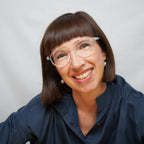 Klammeraffe No.12 blue light glasses in crystal color with longer temples, worn by a woman on a white background.