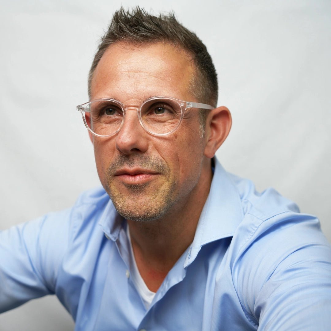 Klammeraffe No.12 blue light reading glasses in crystal color with longer temples, worn by a man on a white background.