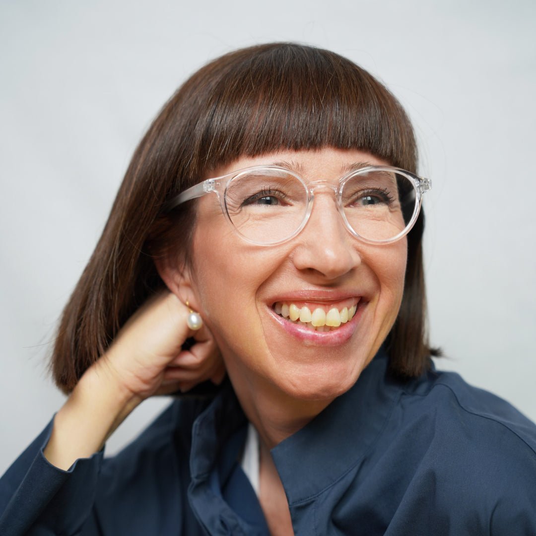 Klammeraffe No.12 blue light reading glasses in crystal color with longer temples, worn by a woman on a white background.