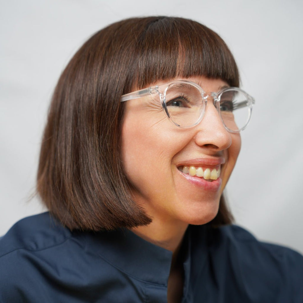 Klammeraffe No.12 reading glasses in crystal color with longer temples, worn by a woman on a white background.
