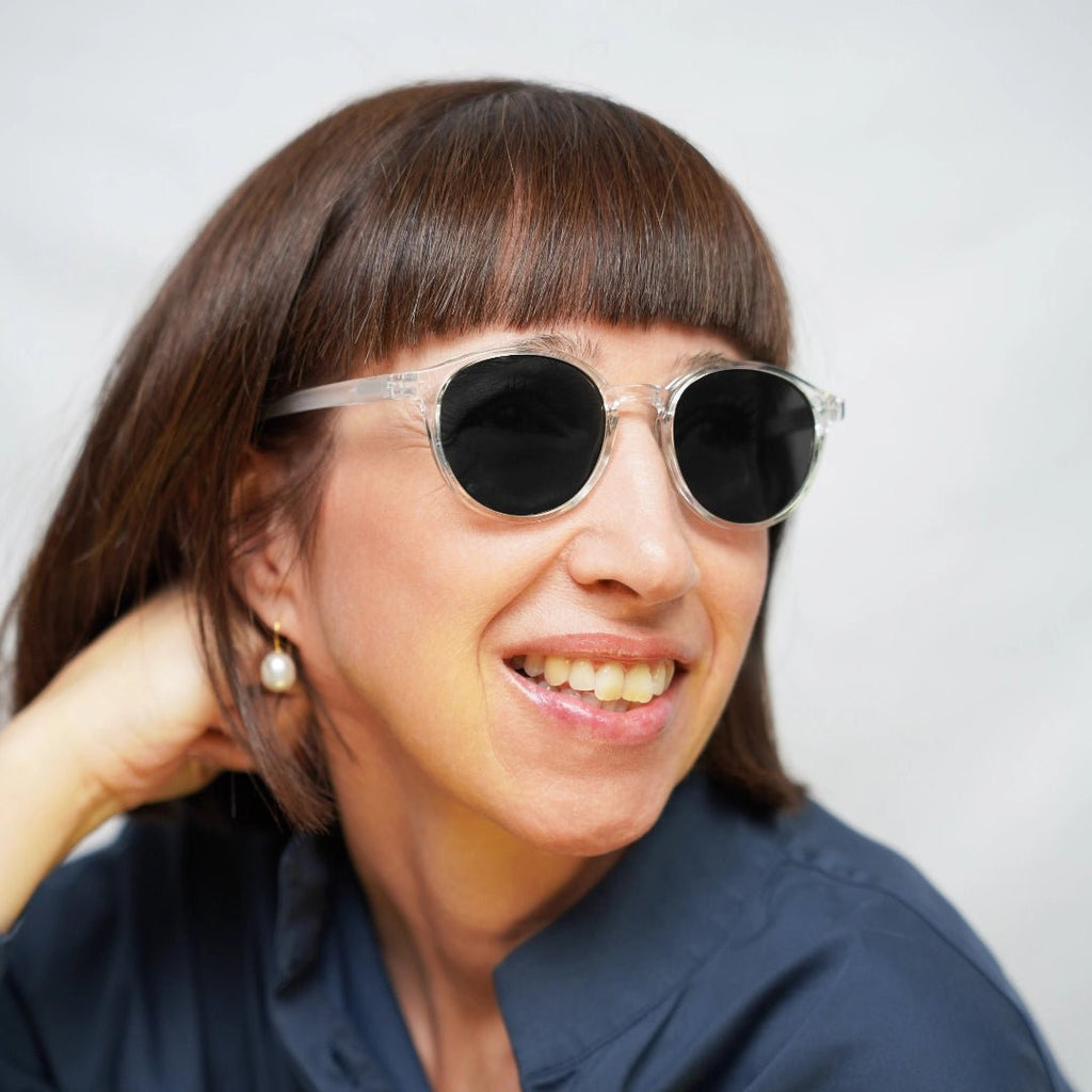 Klammeraffe No.12 reading sunglasses in crystal color with longer temples, worn by a woman on a white background.