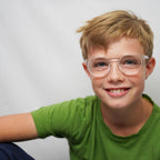Klammeraffe No.13 blue light glasses in crystal color with longer temples, worn by a boy on a white background.