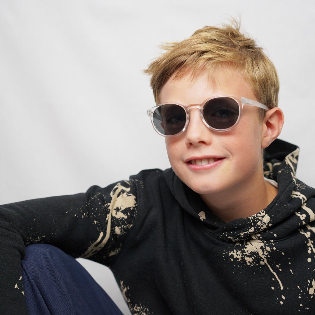 Klammeraffe No.13 sunglasses in crystal color with longer temples, worn by a boy on a white background.
