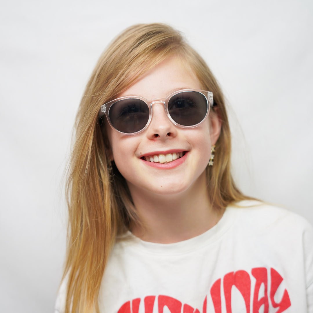 Klammeraffe No.13 sunglasses in crystal color with longer temples, worn by a girl on a white background.