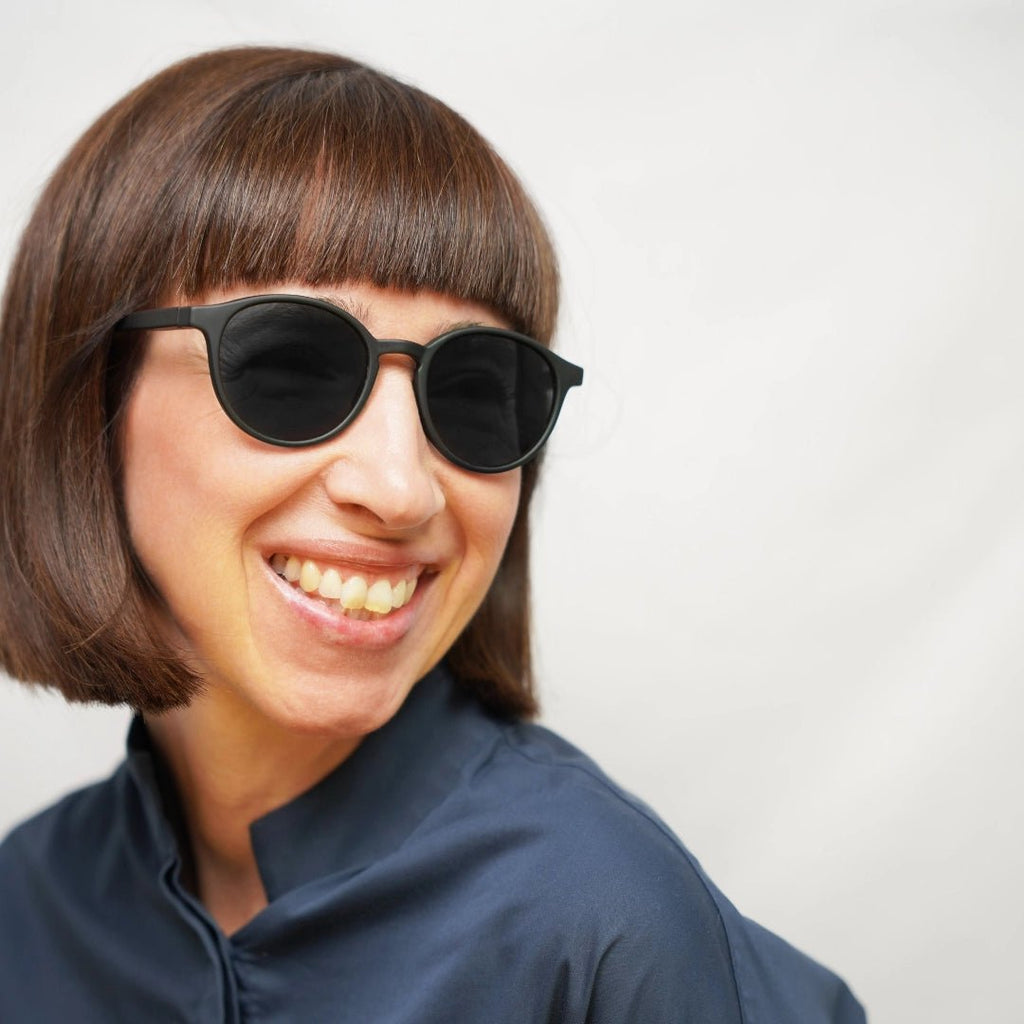 Klammeraffe No.12 sunglasses in black color with longer temples, worn by a woman on a white background.